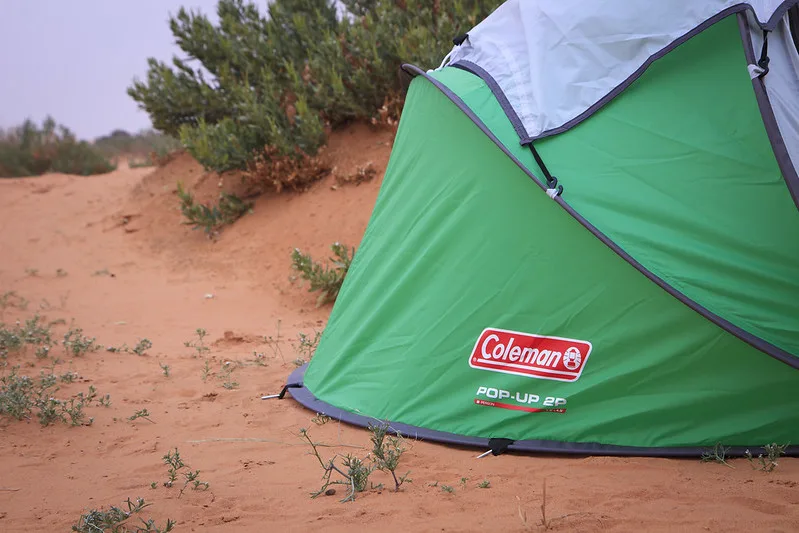 green coleman tent in sandy area